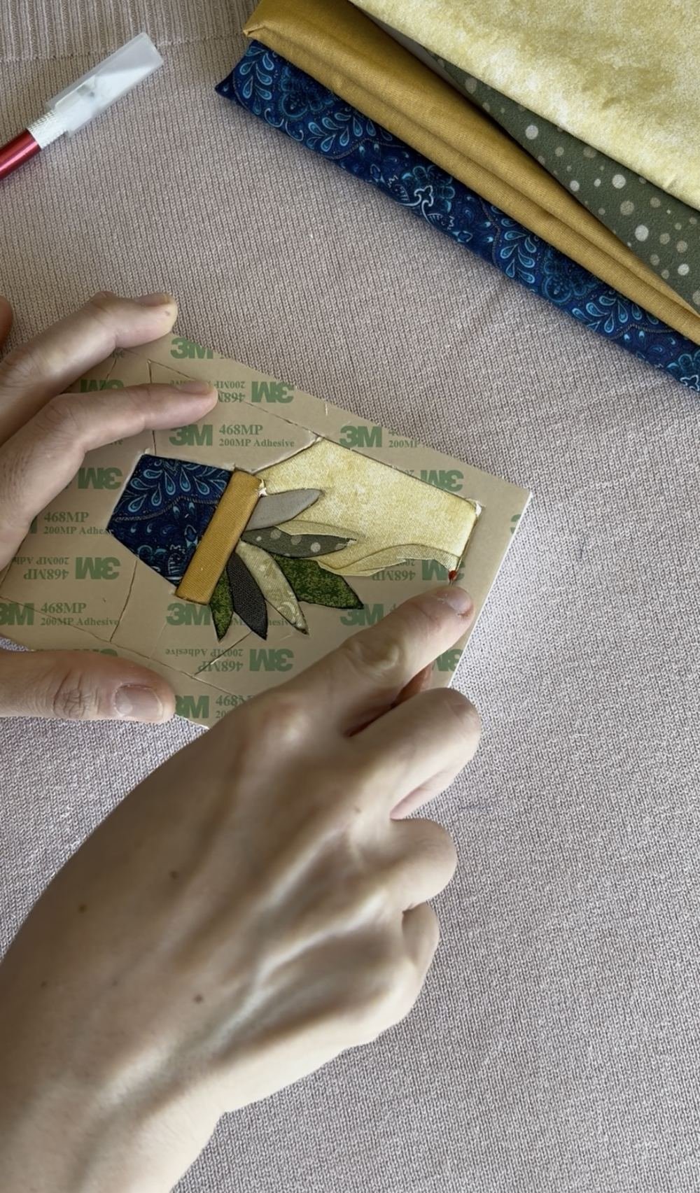 Mãos fixando o tecido com fita dupla-face sobre o molde de um vaso de planta